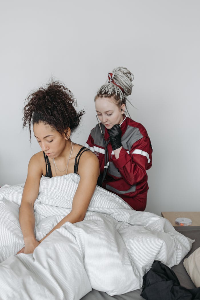 A paramedic provides care to a sick woman in a home setting, reflecting healthcare and support.